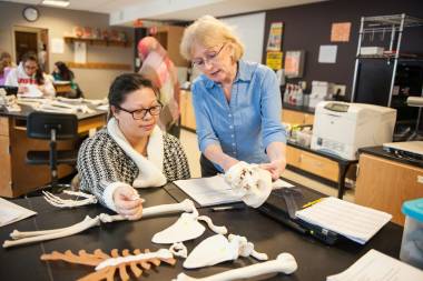 QCC professor demonstrates anatomy on human skeleton