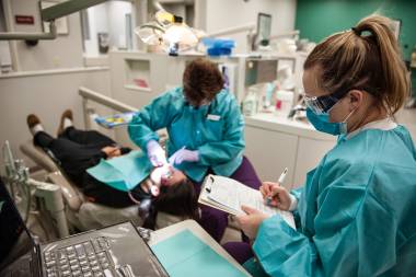 QCC student and professor work on patient in dental clinic